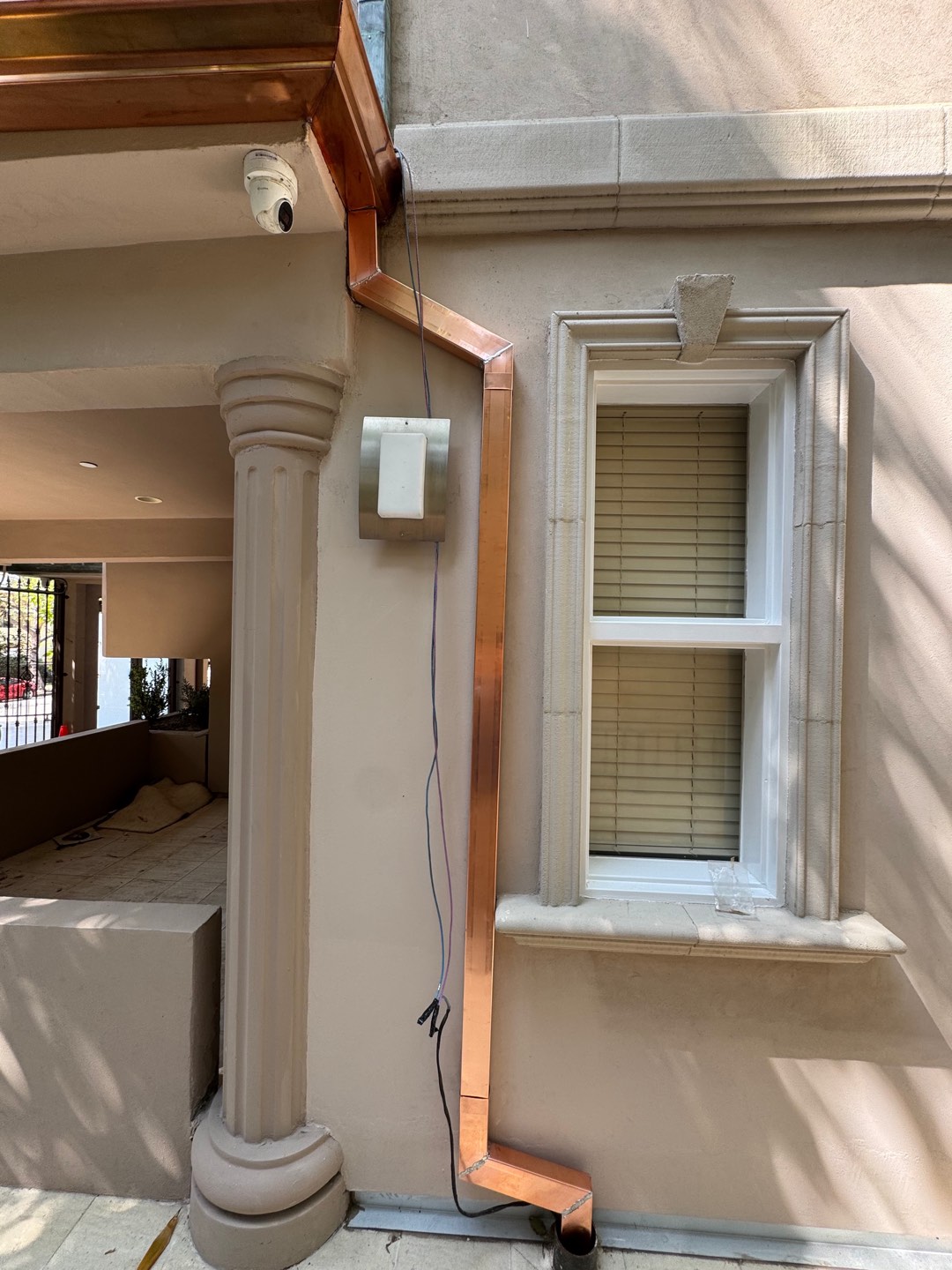 Copper gutter and square copper downspout on a stucco home with stone window trim in the Los Angeles area